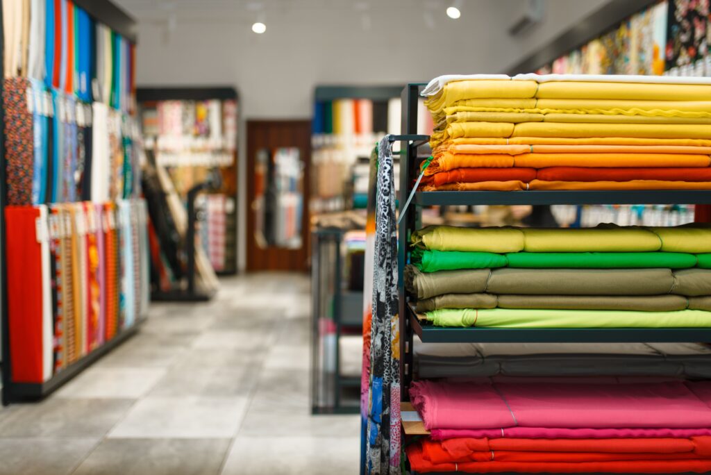 Colorful fabric neatly stacked on shelves in a textile store, showcasing a vibrant and diverse collection of premium materials in a well-lit setting