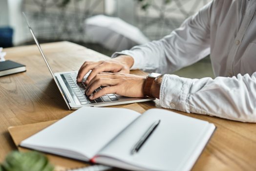 Focused businessman typing on a laptop while developing new content writing strategies for SEO optimization.